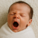 Newborn baby swaddled and yawning – normal baby behavior